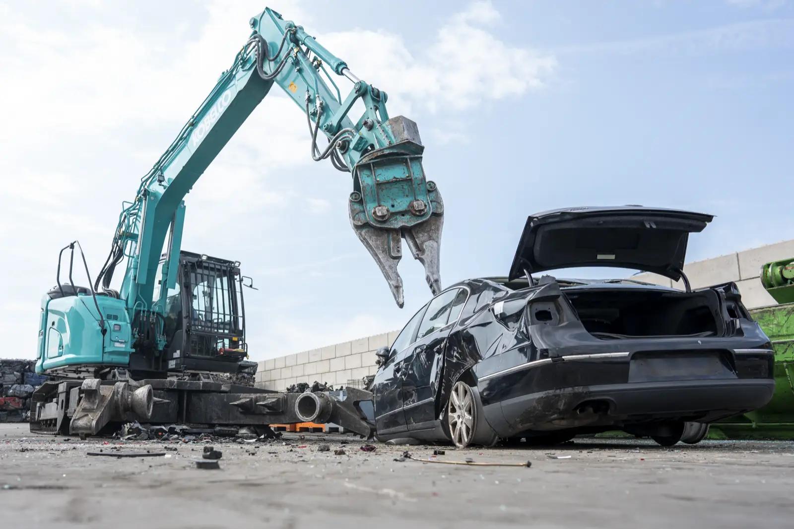 Kobelco SK140SRD zerlegt mit der Greifzange ein Auto auf einem Recyclinghof
