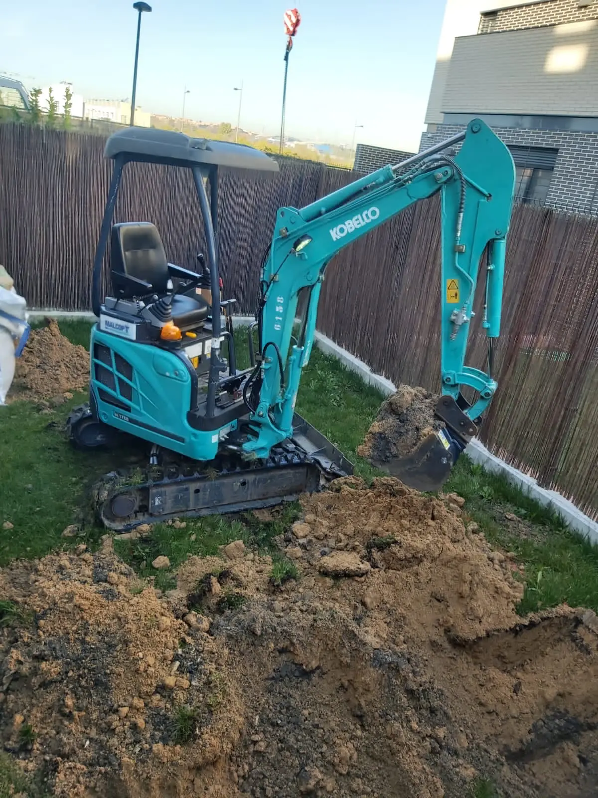 Kobelco SK17SR mit Schutzdach hebt in einem Garten eine Grube aus
