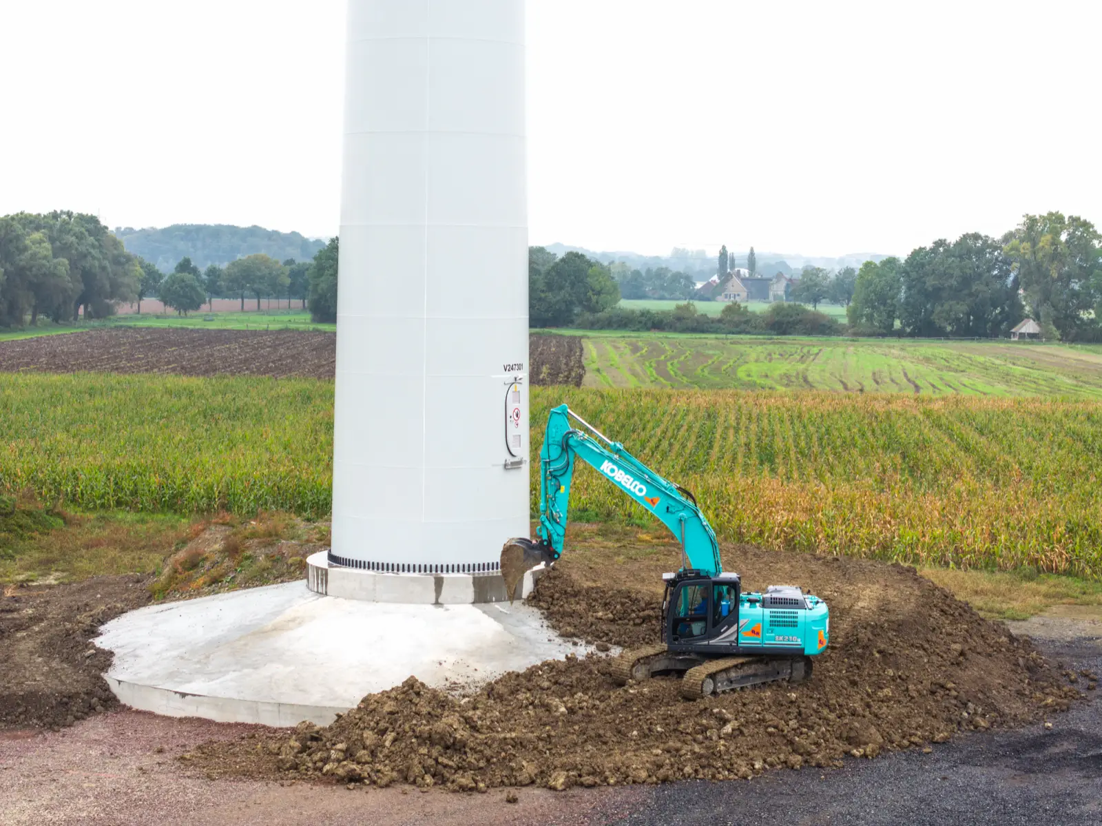 Kobelco SK210LC auf einem Erdwall am Fuß eines Windradturms