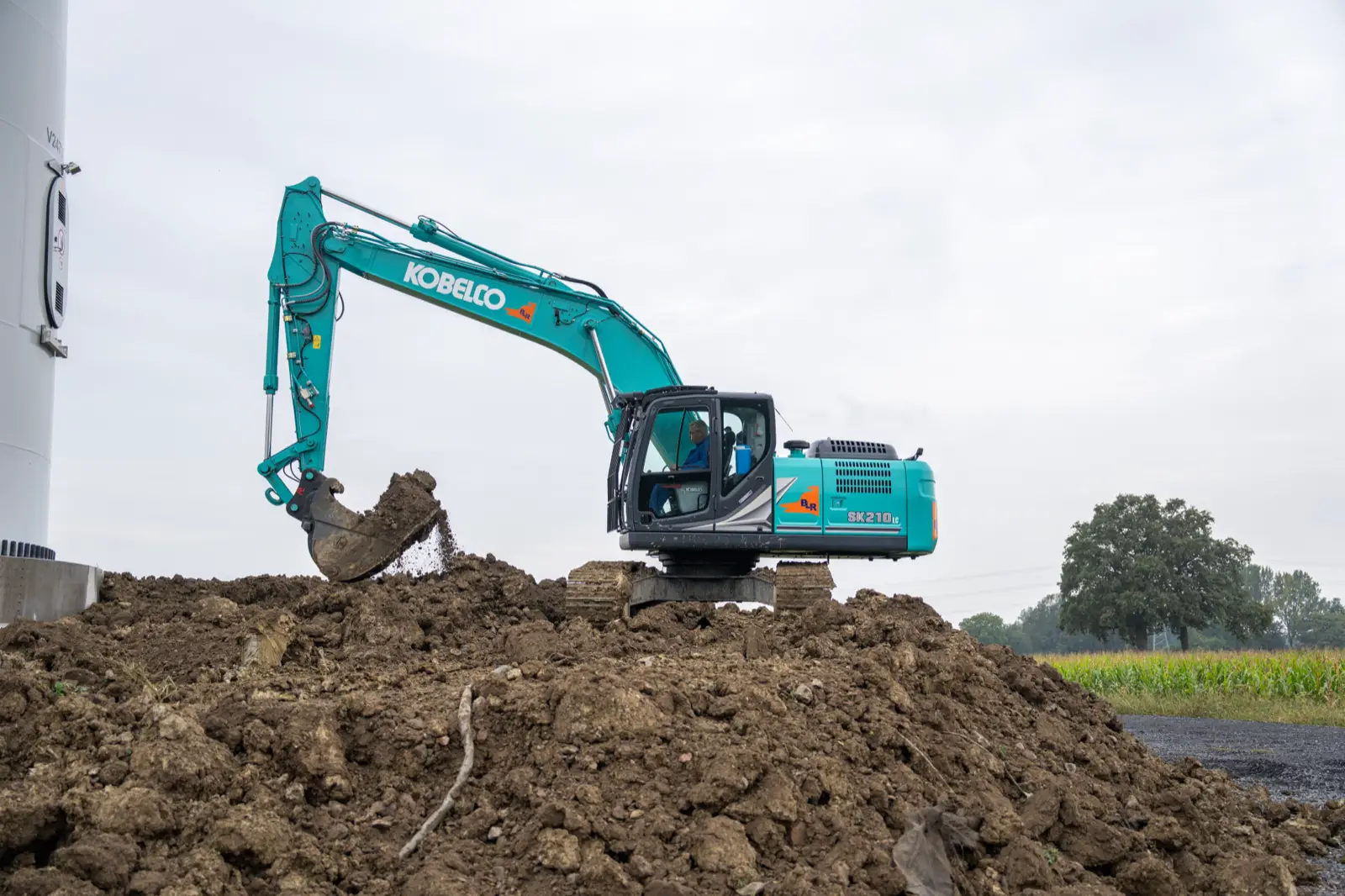 Kobelco SK210LC beim Aufschütten von Erdreich neben einem Windradturm