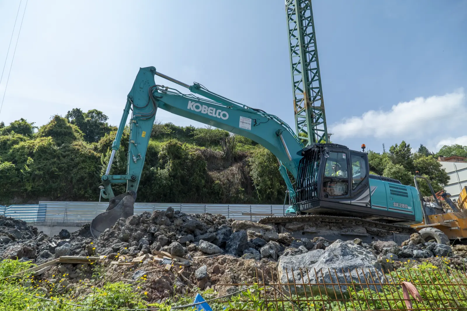 Kobelco SK260LC mit Tieflöffel auf einem Schotterhang neben einem Baukran