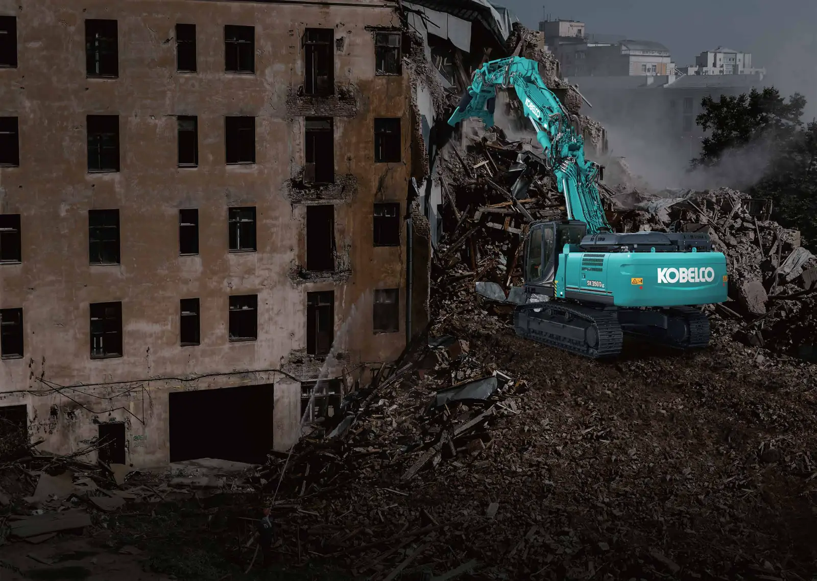 Kobelco SK350DLC mit Abbruchschere vor einem teilweise abgerissenen Wohnhaus