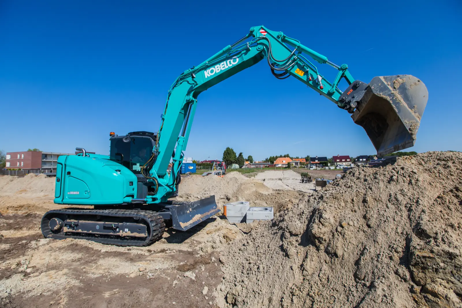 Kobelco SK85MSR hebt mit angehobenem Löffel Erdreich auf einem Baufeld aus