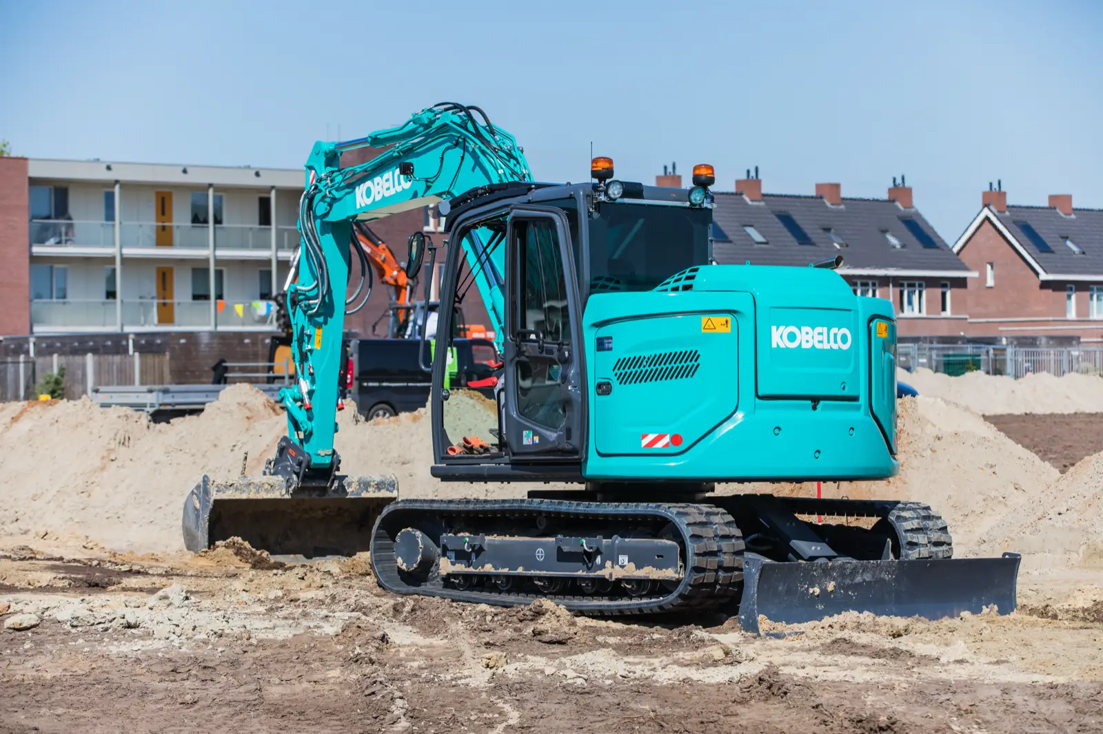 Kobelco SK85MSR auf einer Baustelle vor Wohnhäusern