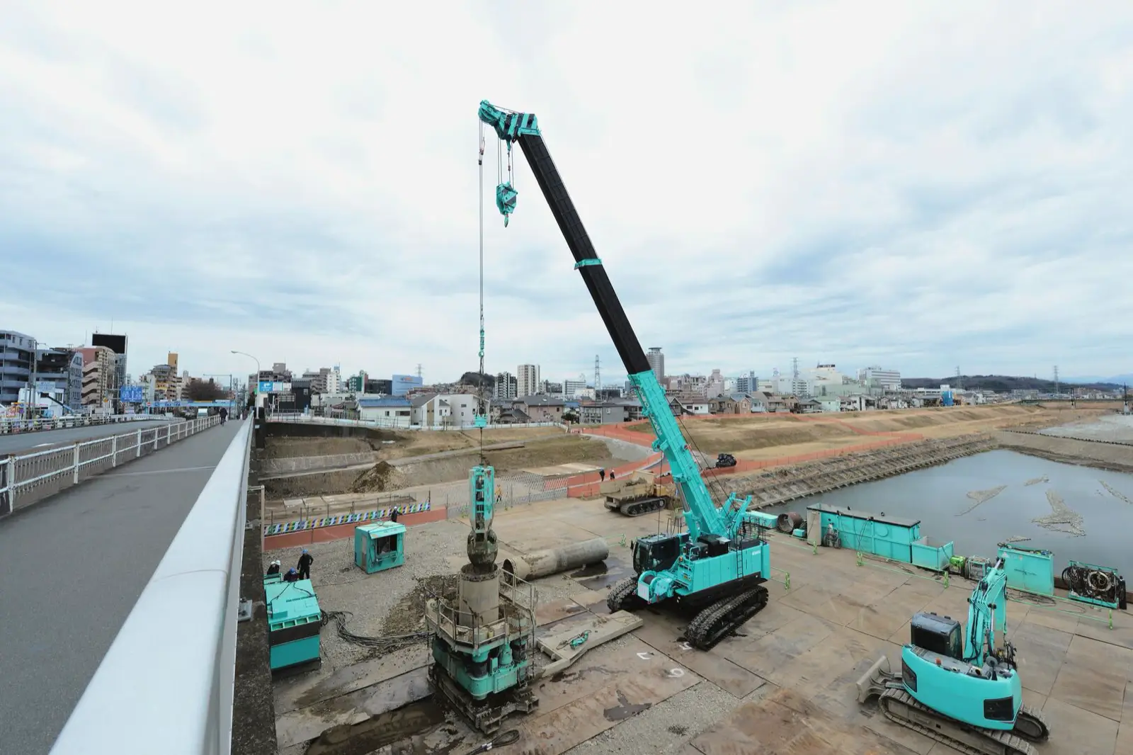 Kobelco TKE750G mit ausgefahrenem Teleskopausleger bei Gründungsarbeiten am Flussufer