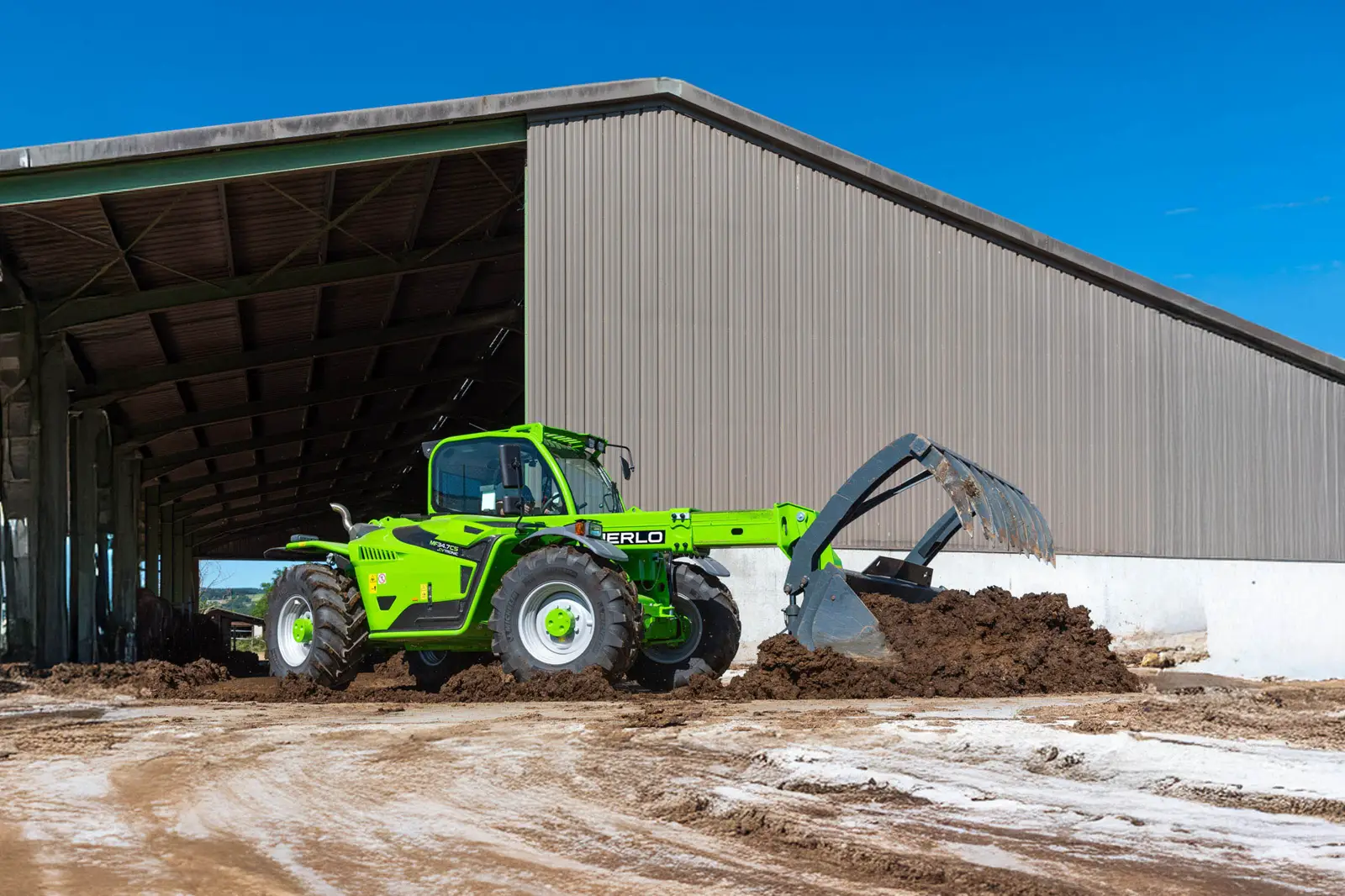 Baureihenbild zu Merlo MF 34.7 CS-140: Merlo Multifarmer MF 34 mit Schaufel vor einer Maschinenhalle