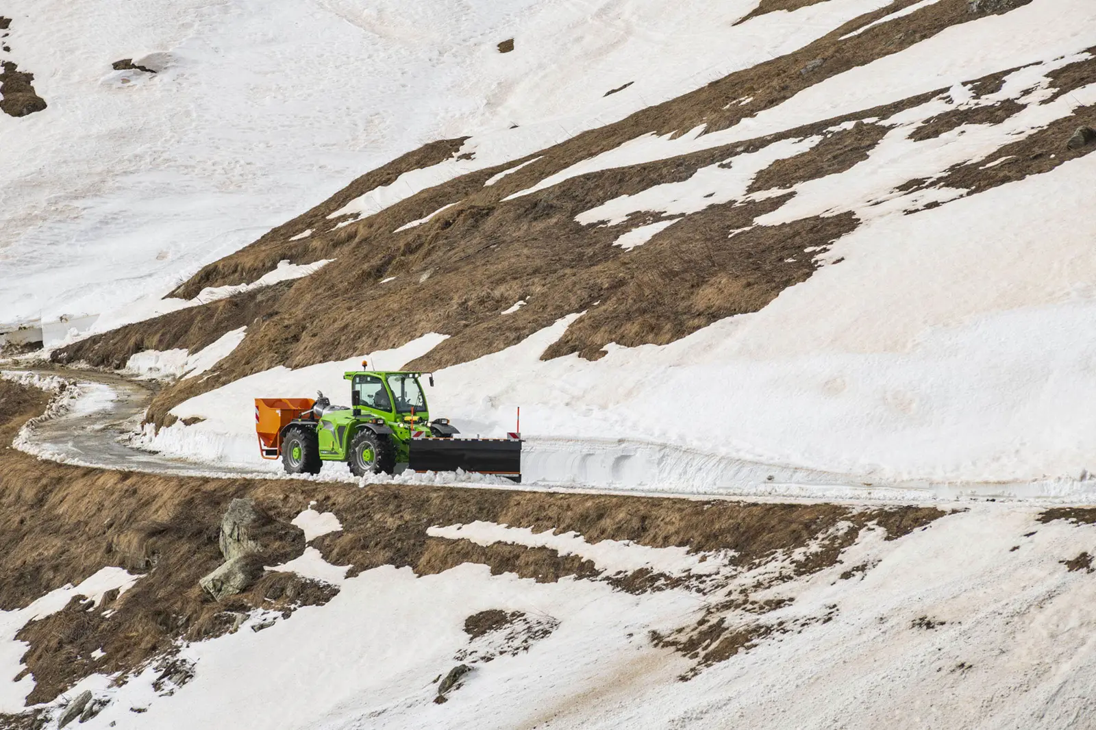 Merlo Multifarmer MF 44 mit Streuer und Schneeschild auf einer Bergstraße