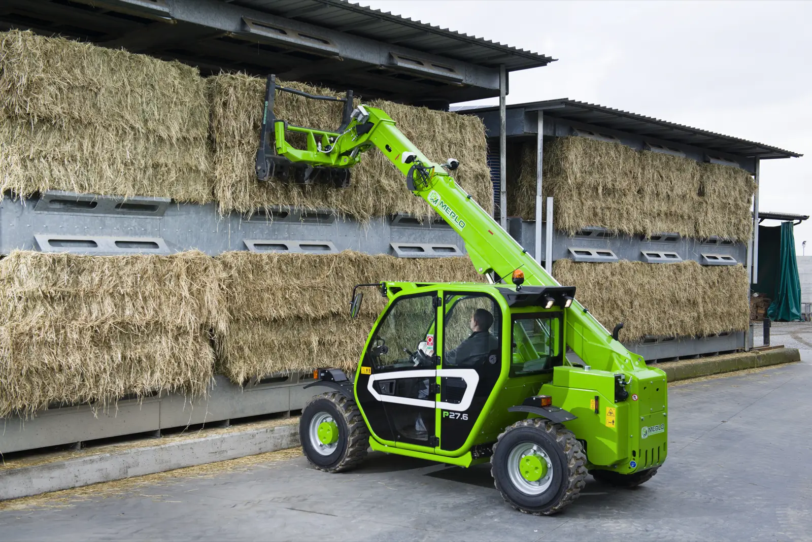 Merlo P27.6 stapelt Heuballen unter einem Hallendach