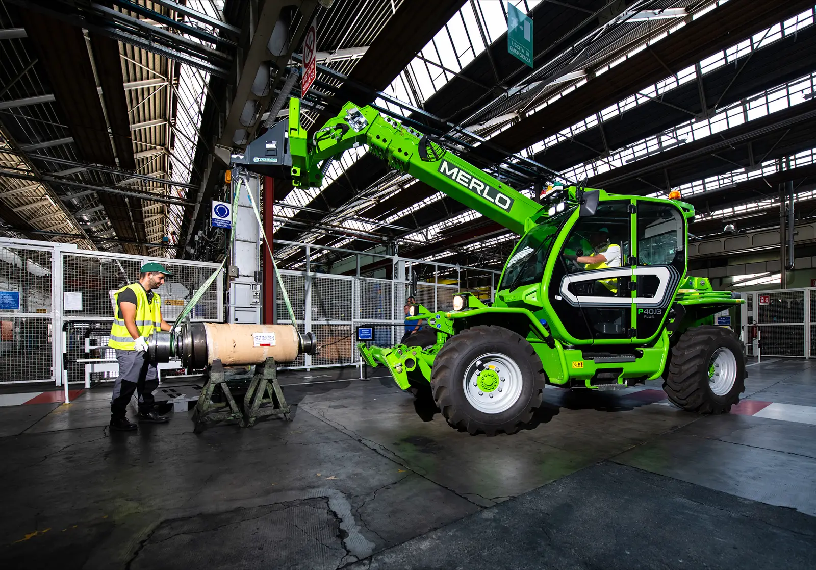 Merlo Panoramic 40.13 hebt eine Papierrolle in einer Werkshalle, daneben ein Arbeiter