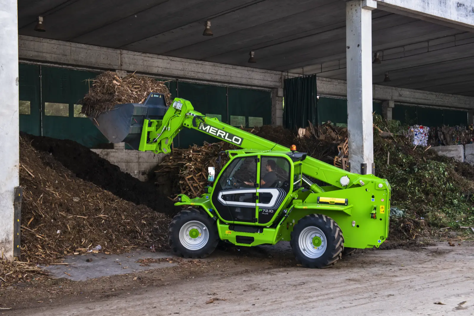 Merlo P72.10 mit Schaufel an einem Haufen Grünschnitt