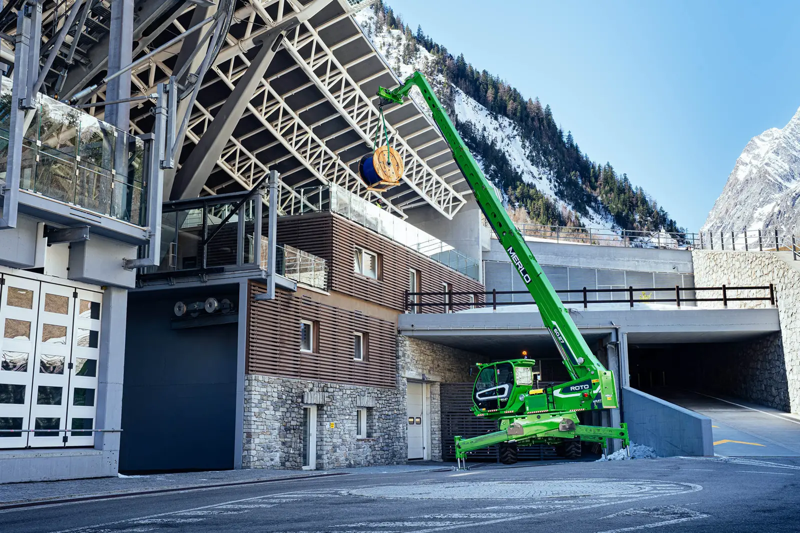 Baureihenbild zu Merlo R 75.25 S PLUS: Merlo Roto mit steil aufgerichtetem Teleskoparm an einem Gebäude im Gebirge