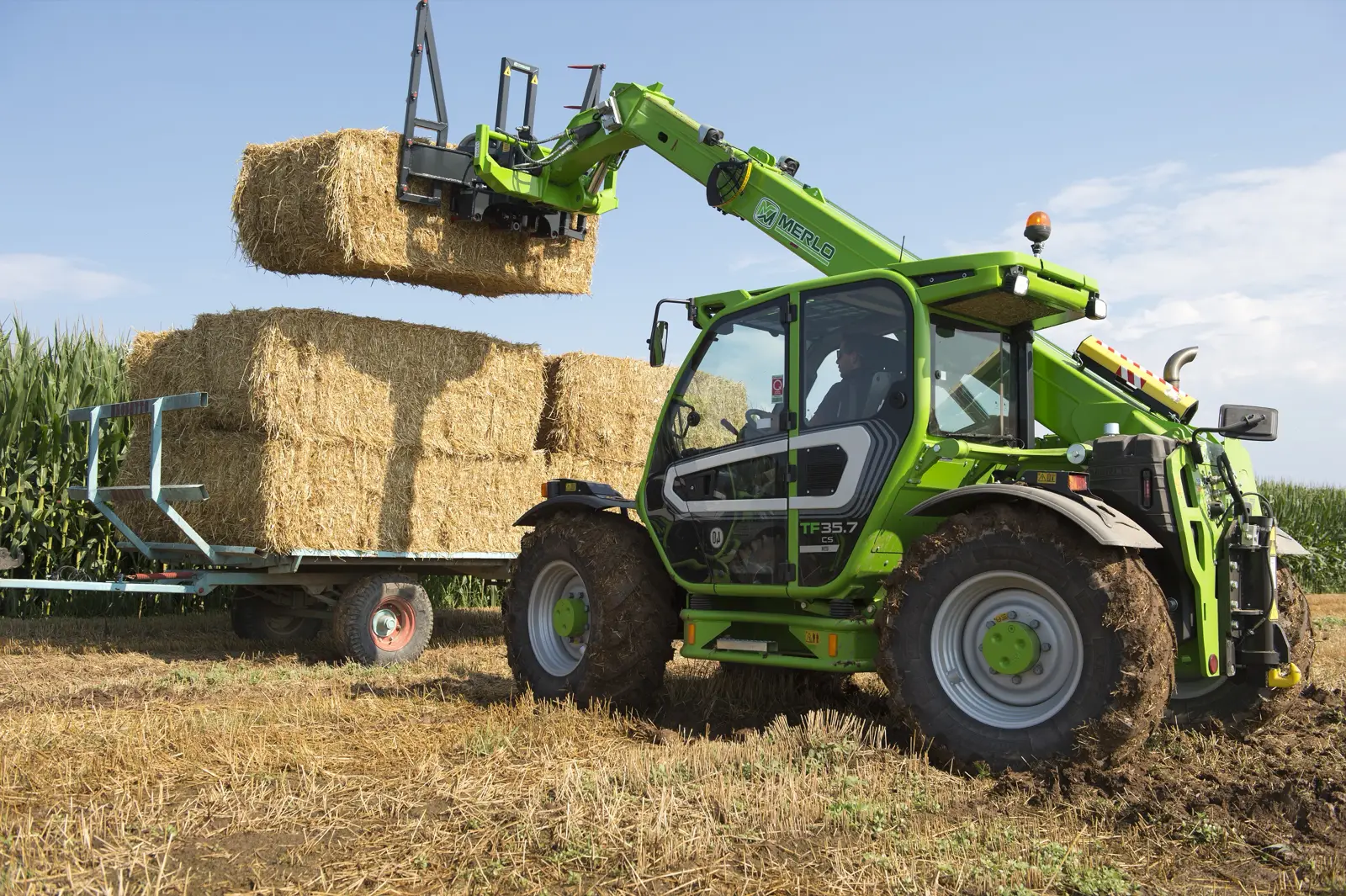 Merlo TF35.7 CS setzt einen Strohballen auf einen Anhänger