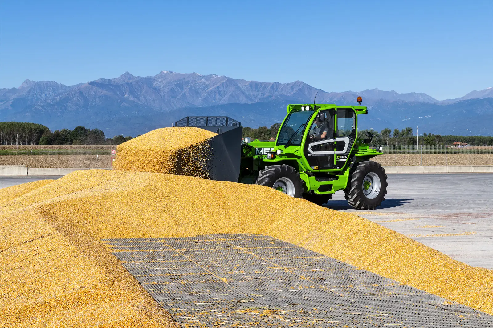 Baureihenbild zu Merlo TF 38.10 TT-136: Merlo TF38.10 mit Schaufel auf einem Maishaufen vor Bergkulisse