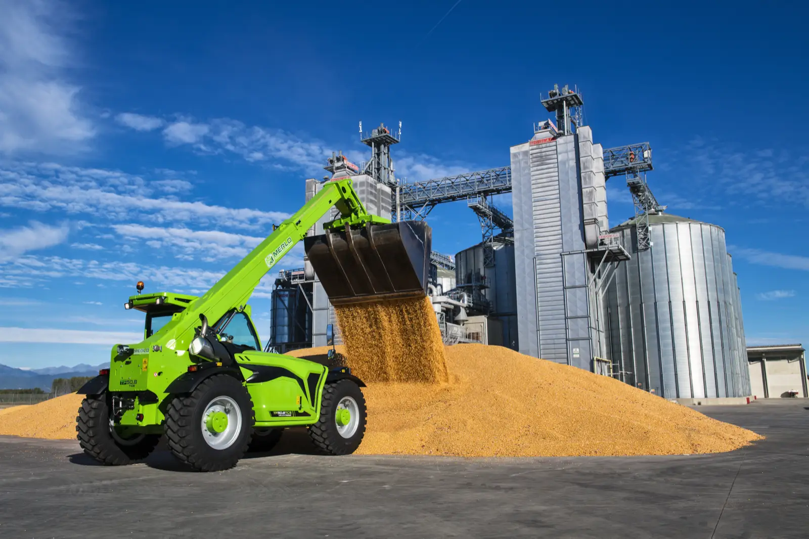 Baureihenbild zu Merlo TF 50.8 T-170-HF: Merlo TF50.8 mit hoch ausgefahrener Schaufel vor Getreidesilos