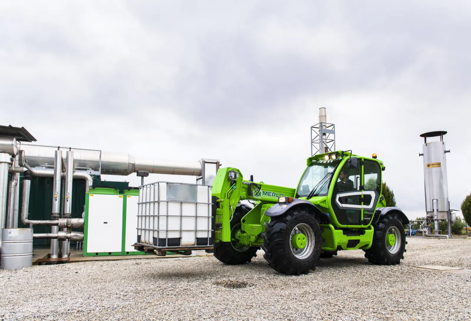 Baureihenbild zu Merlo TF 65.9 T-CS-170-CVTRONIC-HF: Merlo TF65.9 mit Palettengabel neben einem Tank-Container auf einem Betriebsgelände