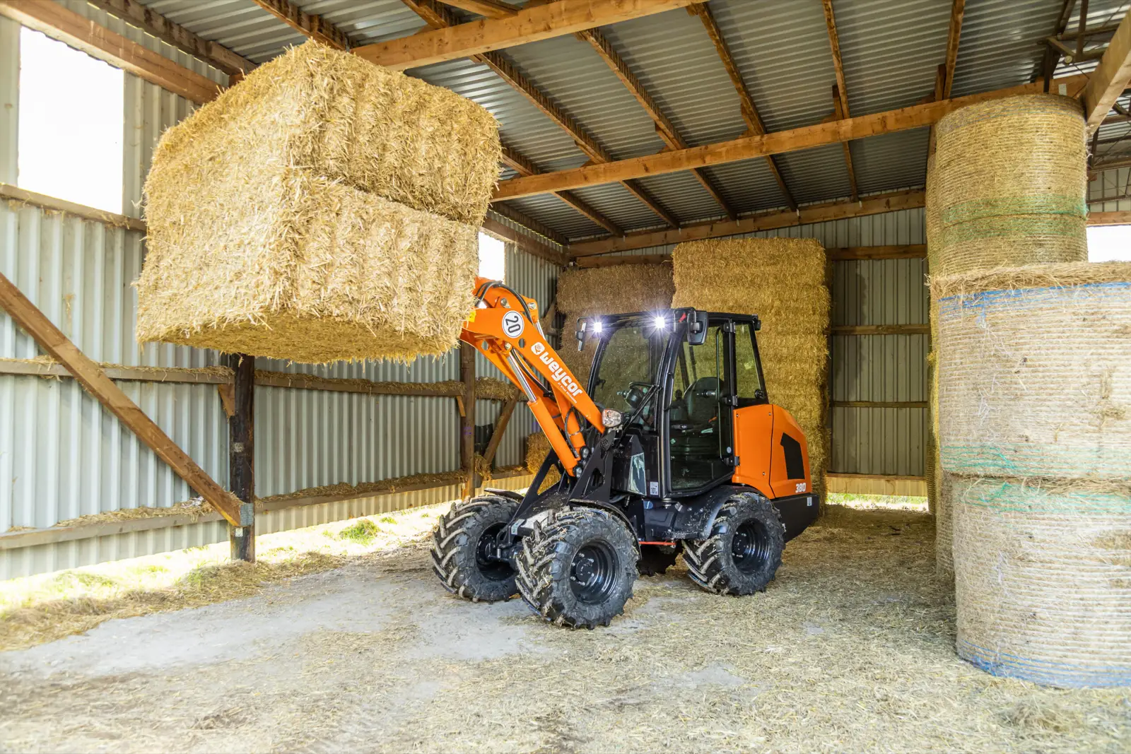 Baureihenbild zu Weycor 380: Weycor 380 stapelt einen Strohballen unter einem Hallendach