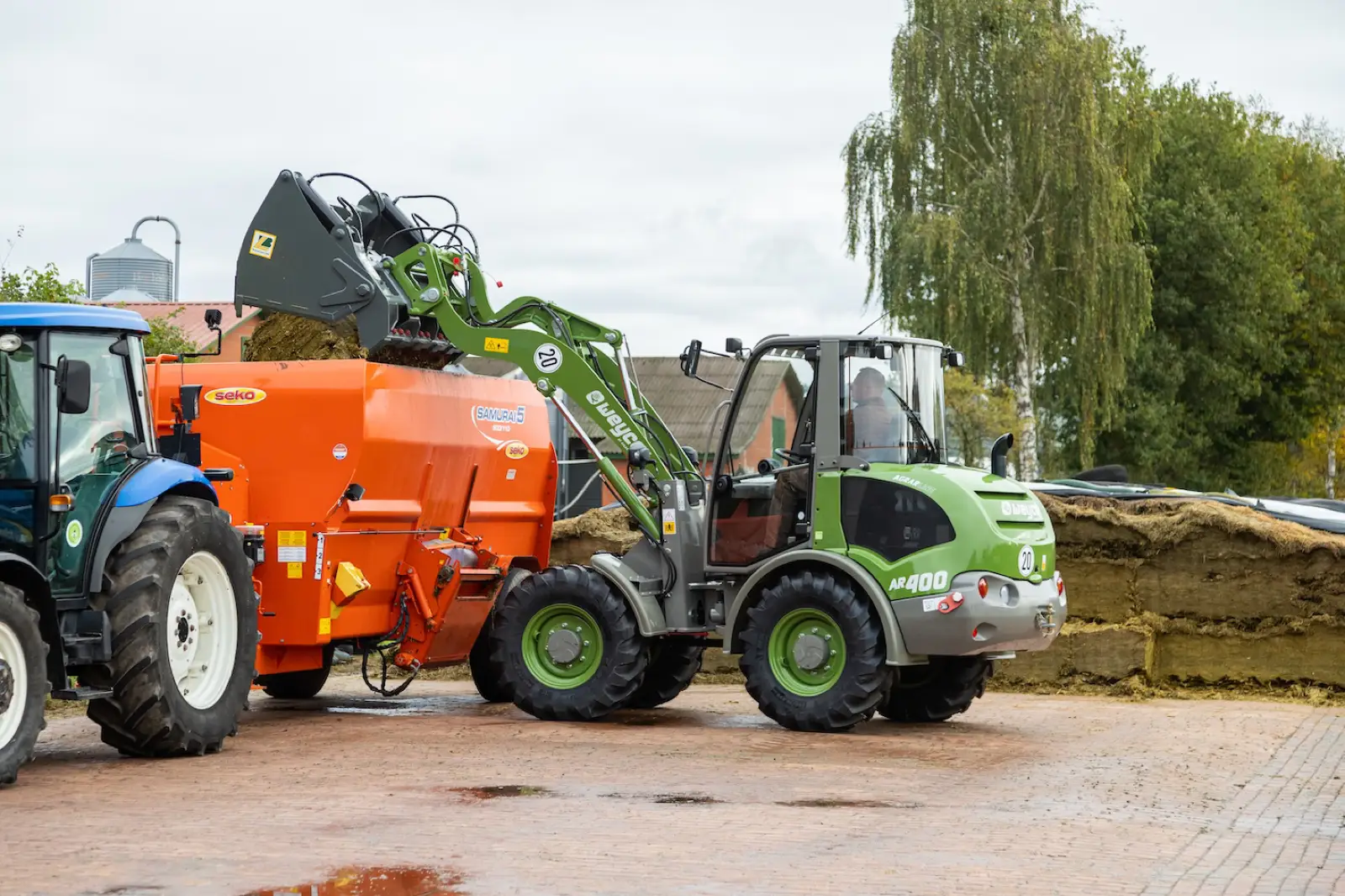 Weycor AR400 Agrarline befüllt einen Futtermischwagen neben einem Traktor