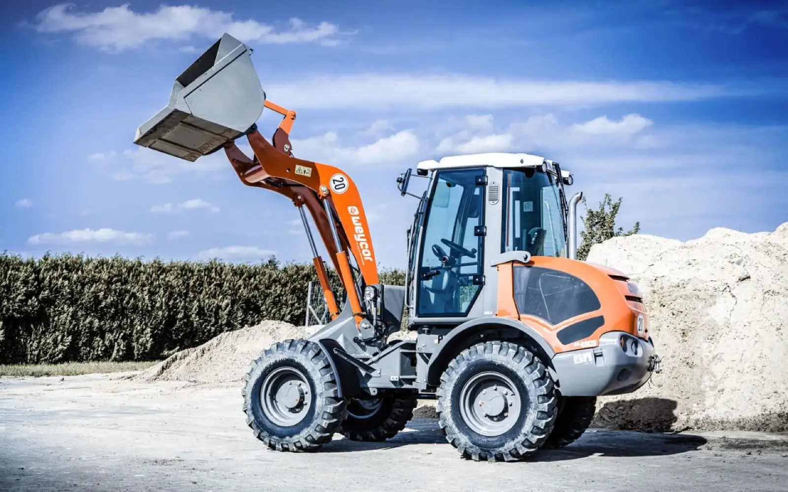 Weycor AR480S mit angehobener Schaufel an einem Sandhaufen