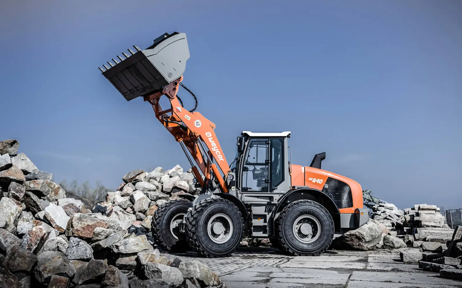 Weycor AR640 hebt die Schaufel vor einem Steinhaufen